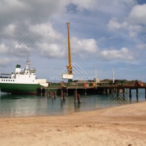 Wharf with Moored Vessel and Working Crane Beside Calm Coastal Waters. Seisia, Australia.