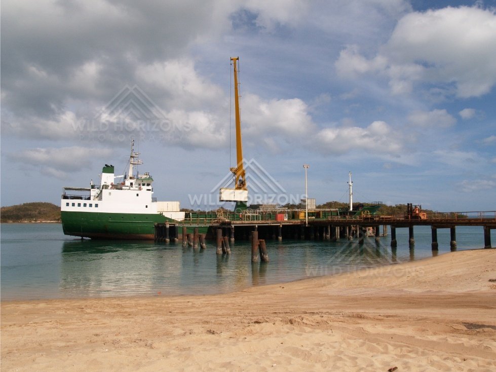 Wharf with Moored Vessel and Working Crane Beside Calm Coastal Waters. Seisia, Australia.