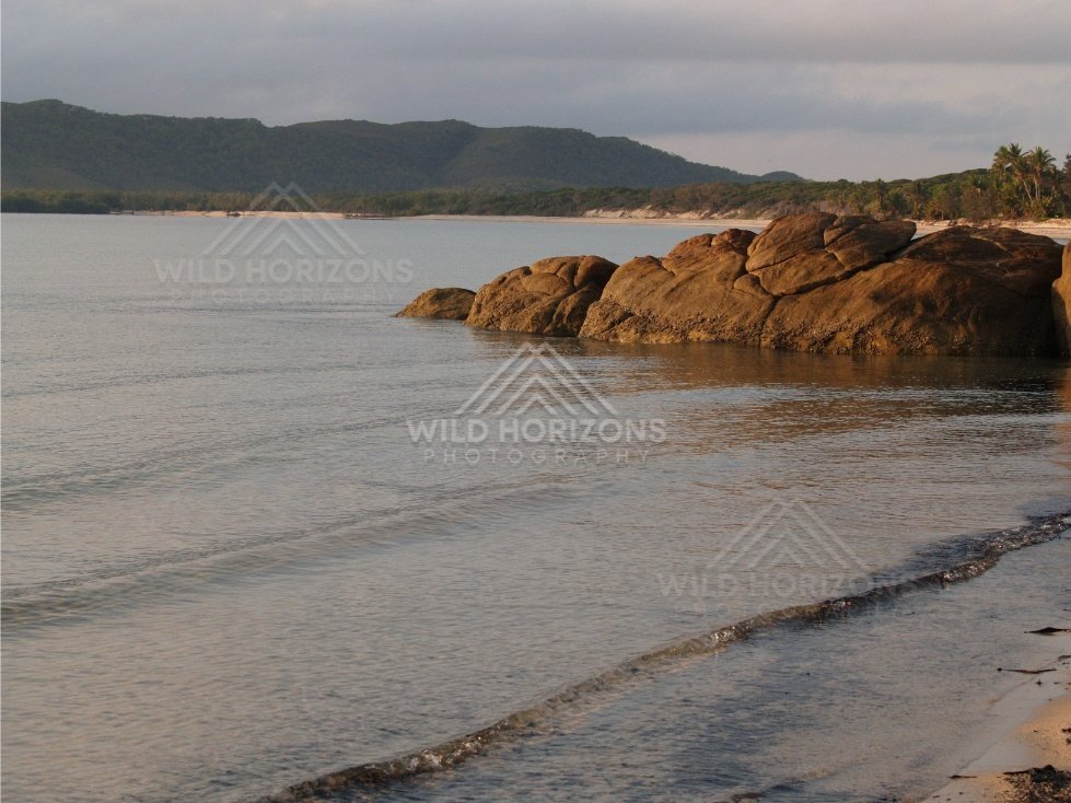 Calm shoreline with granite outcrops and small waves in a sheltered bay. Portland Roads, Australia.