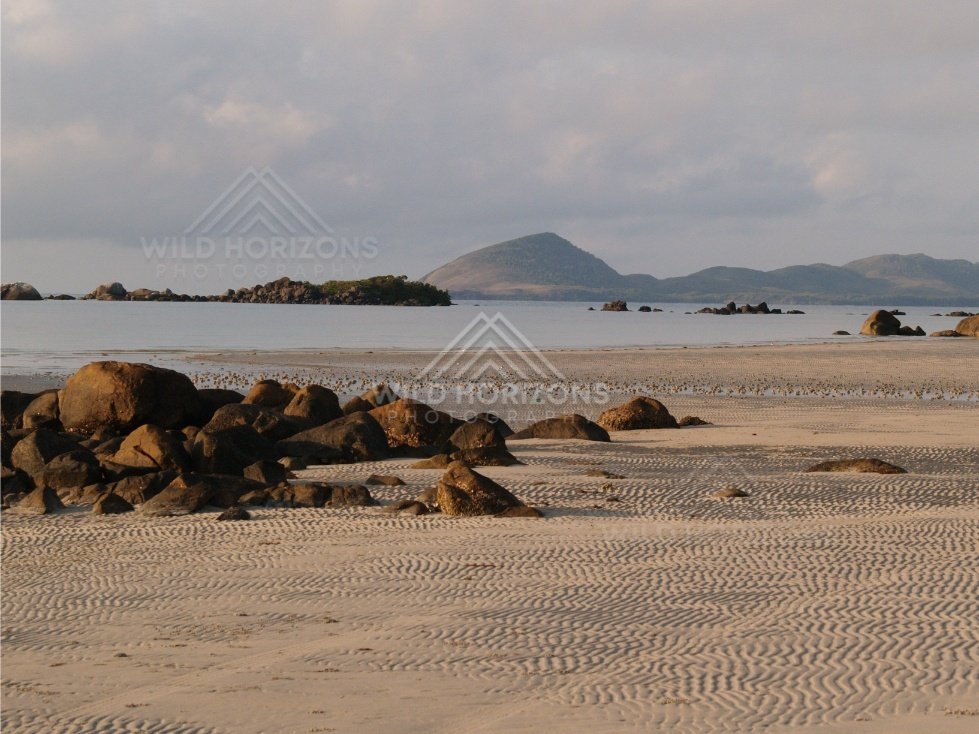 Tidal sand flats with scattered rocks and islands under a cloudy sky. Portland Roads, Australia.