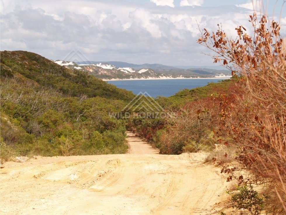 Sandy track descending toward the sea between coastal hills. Elim Beach, Australia.
