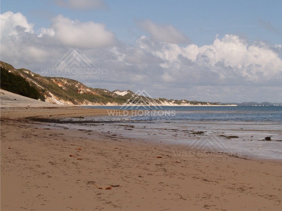 Long sandy shoreline with dune cliffs and low-tide flats. Elim Beach, Australia.
