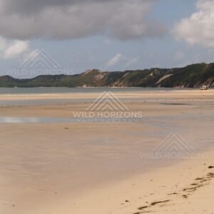 Broad tidal flats with coastal headlands under a cloudy sky. Elim Beach, Australia.