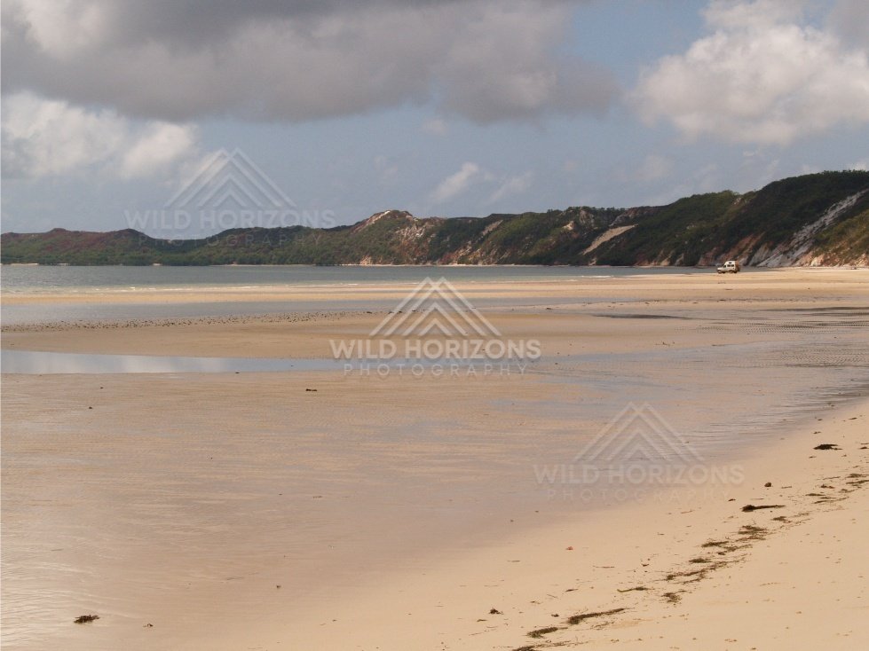 Broad tidal flats with coastal headlands under a cloudy sky. Elim Beach, Australia.
