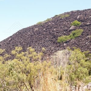 Dark granite boulders of Black Mountain above sparse vegetation. Black Mountain, Australia.