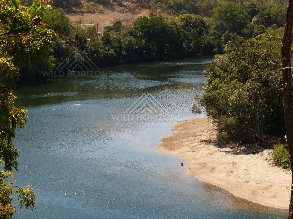 Sandy bend of the Bloomfield River beneath forested hills. Bloomfield River, Australia.
