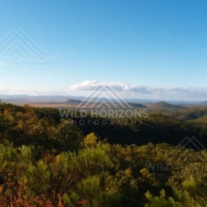 Blue sky above a wide valley of forested hills and distant ranges. Queensland, Australia.