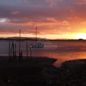 Sunset light reflecting on water near a small wharf. Cooktown, Australia.
