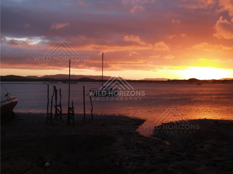 Sunset light reflecting on water near a small wharf. Cooktown, Australia.