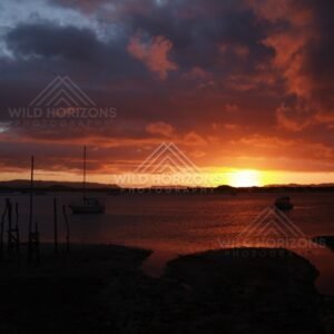 Deep red sunset sky above an inlet and moored boats. Cooktown, Australia.