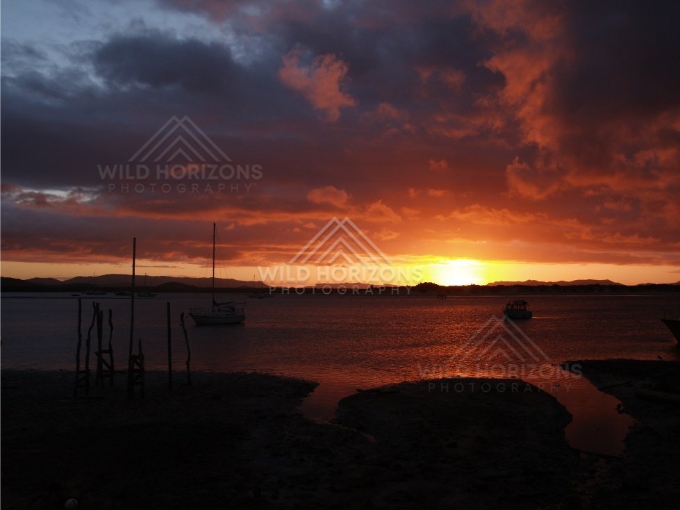 Deep red sunset sky above an inlet and moored boats. Cooktown, Australia.