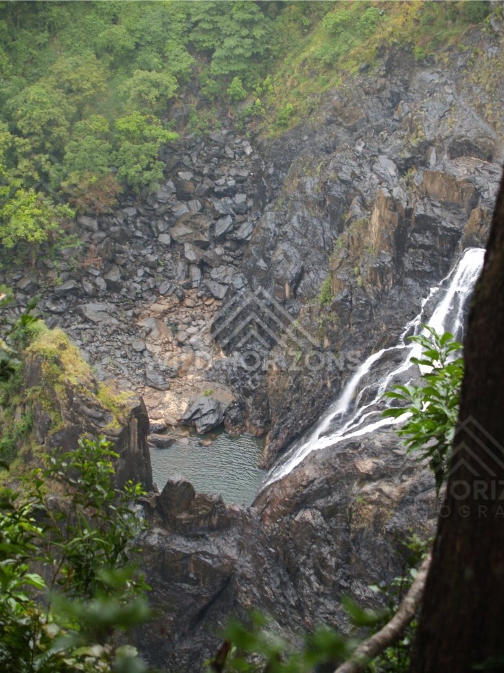 Waterfall dropping through dark rock into a narrow rainforest gorge. Kuranda, Australia.