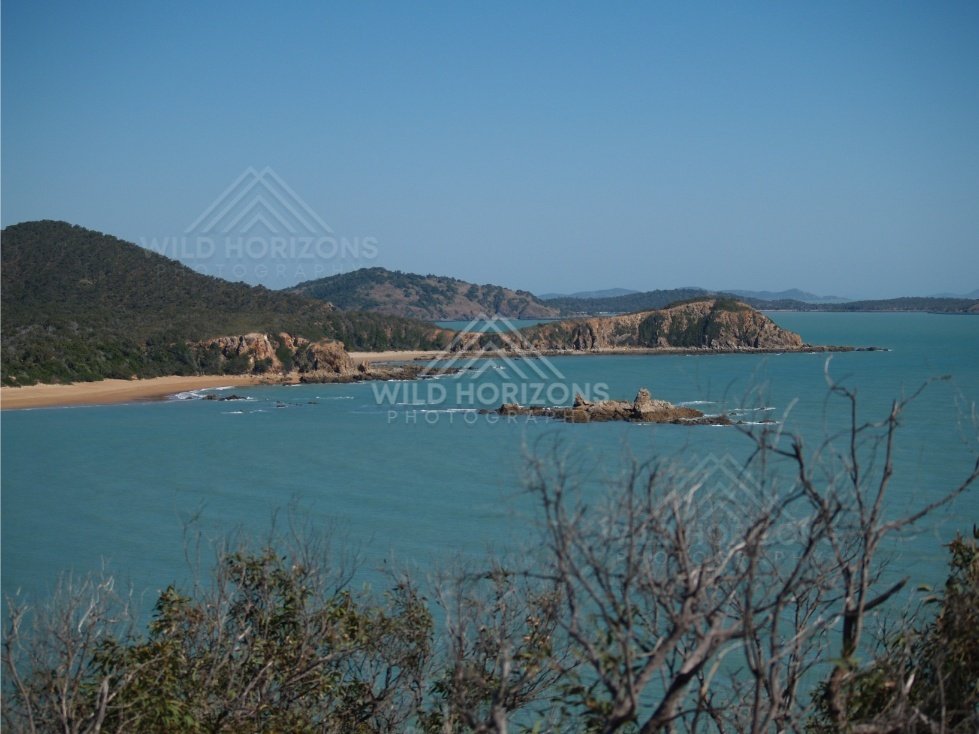 Wide coastal view with shrubs in foreground. Stanage Bay, Australia.
