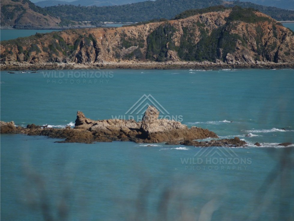 Offshore rocks beneath clear sky. Stanage Bay, Australia.