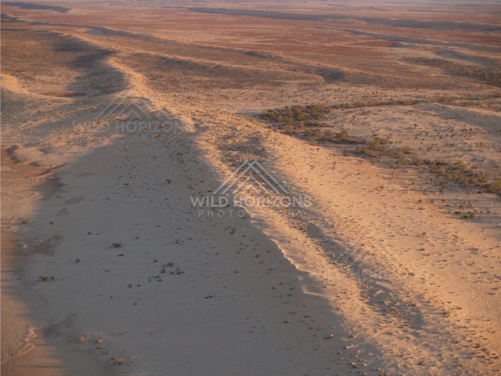 Low aerial view of dune edge and clay pan. Simpson Desert, Australia.