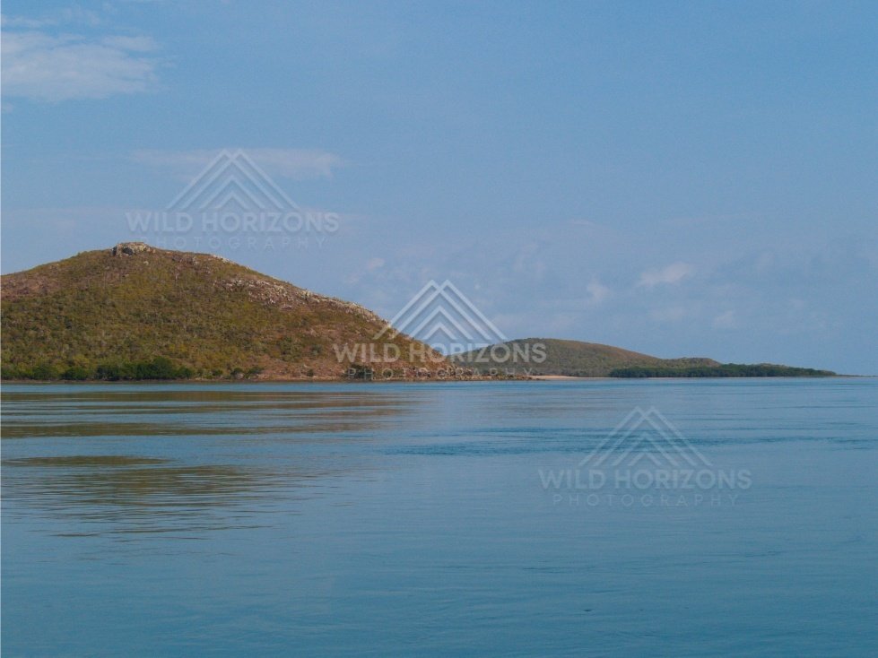 Rounded hill island across a glassy tropical channel. Cape York, Queensland, Australia.