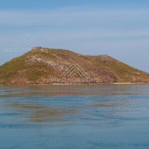 Brown hill island rising from turquoise sea. Cape York, Queensland, Australia.