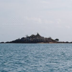 Rocky islet with scattered trees in open sea. Cape York, Queensland, Australia.