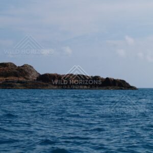 Rocky coastal point above blue ocean. Cape York, Queensland, Australia.