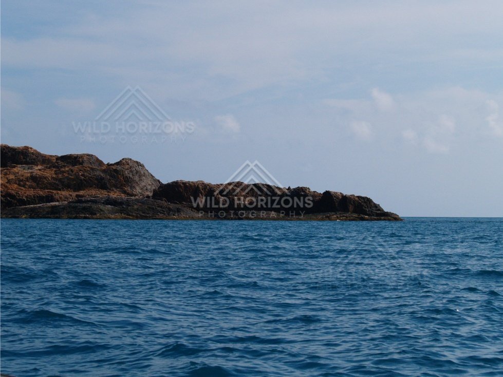 Rocky coastal point above blue ocean. Cape York, Queensland, Australia.