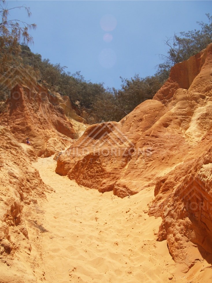 Sandy track between coloured sandstone cliffs. Rainbow Beach, Australia.