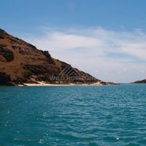 Sloping rocky headland beside clear tropical water. Cape York, Queensland, Australia.