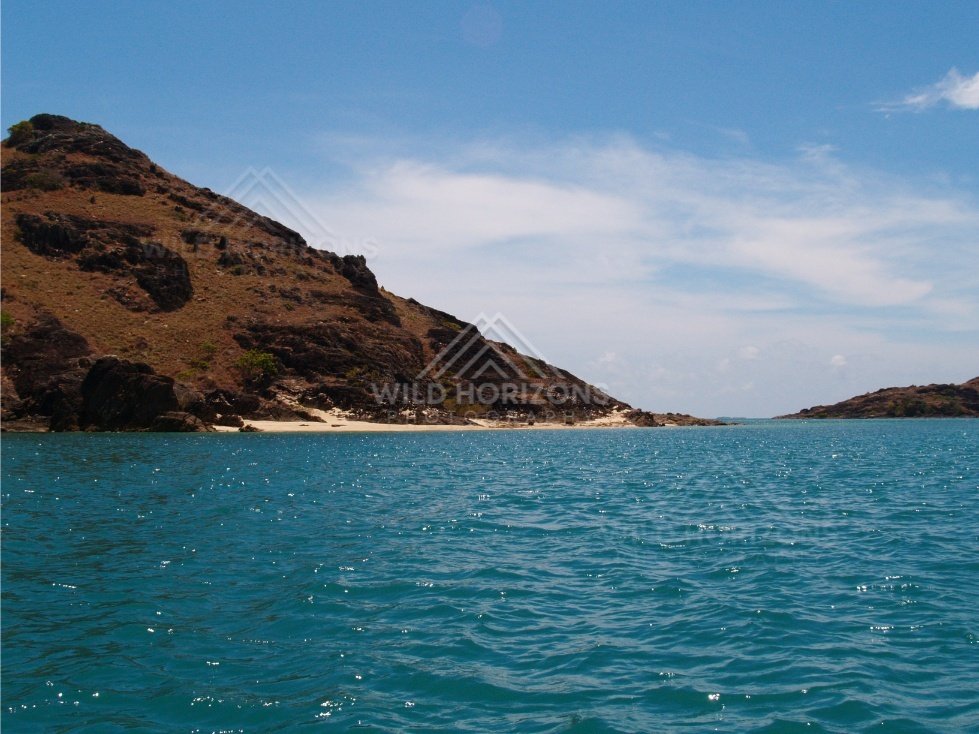 Sloping rocky headland beside clear tropical water. Cape York, Queensland, Australia.