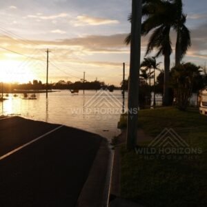 Flooded Bundaberg street at sunset with parked vehicles. Bundaberg, Australia.