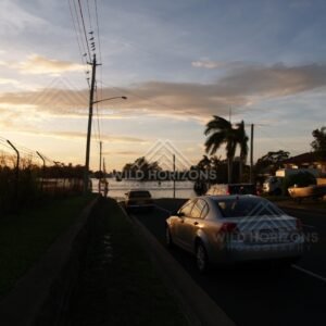Cars driving through shallow floodwater at dusk. Bundaberg, Australia.
