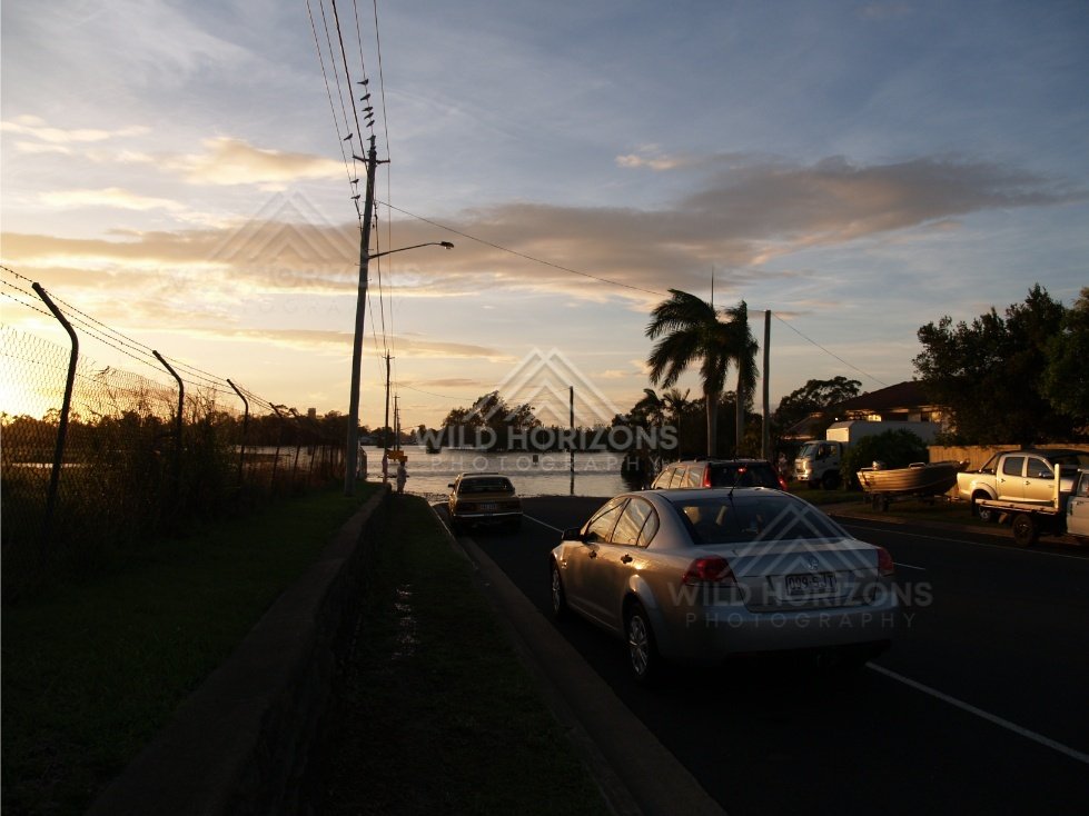 Cars driving through shallow floodwater at dusk. Bundaberg, Australia.