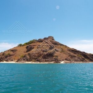 Rounded island with dry grasses and rocky outcrops. Cape York, Queensland, Australia.