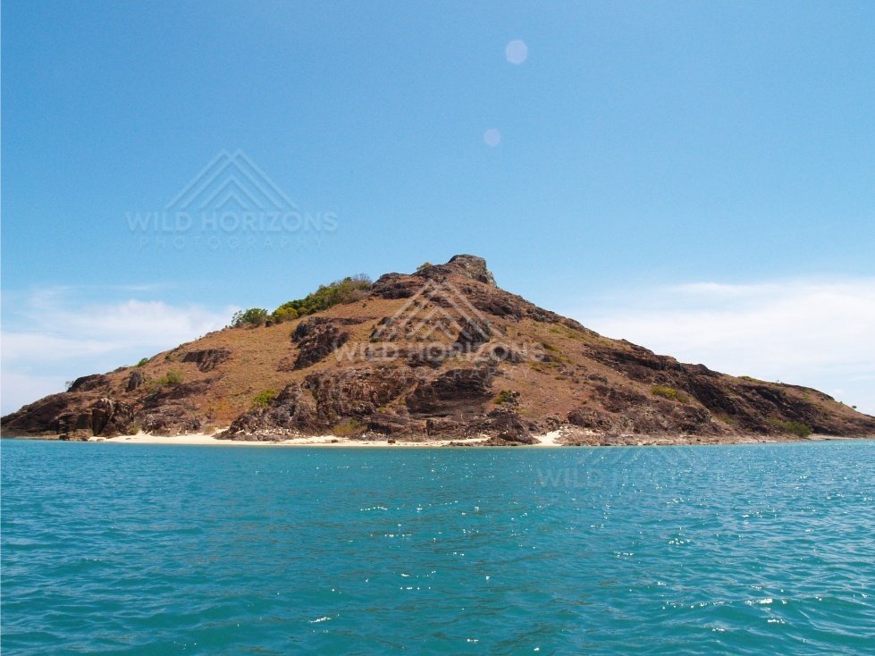 Rounded island with dry grasses and rocky outcrops. Cape York, Queensland, Australia.