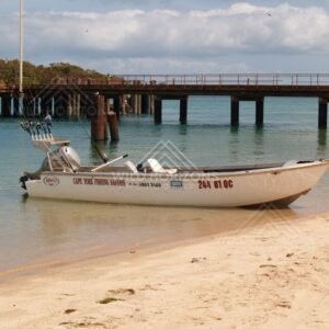 Aluminium boat on sand in front of a timber wharf. Seisia, Queensland, Australia.