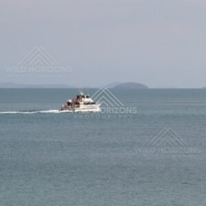 Small boat crossing a wide bay with islands beyond. Seisia, Queensland, Australia.