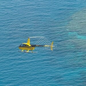 Yellow helicopter flying over turquoise reef waters. Thursday Island, Queensland, Australia.