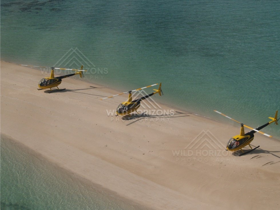 Three yellow helicopters parked on a sandy spit. Thursday Island, Queensland, Australia.