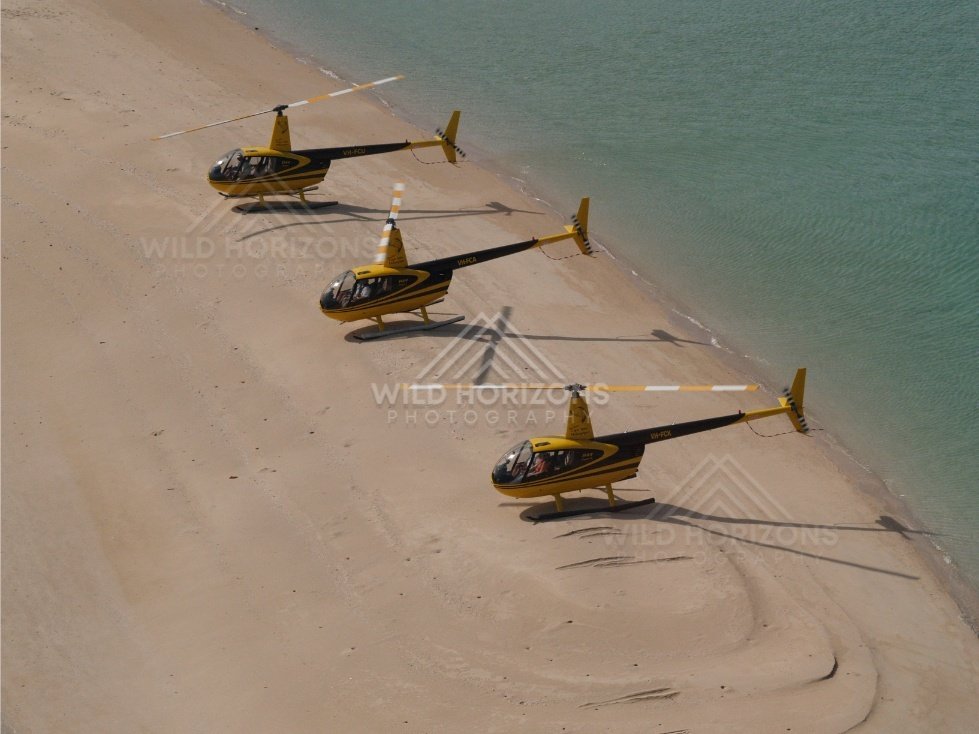 Two helicopters resting on sand near the sea. Thursday Island, Queensland, Australia.