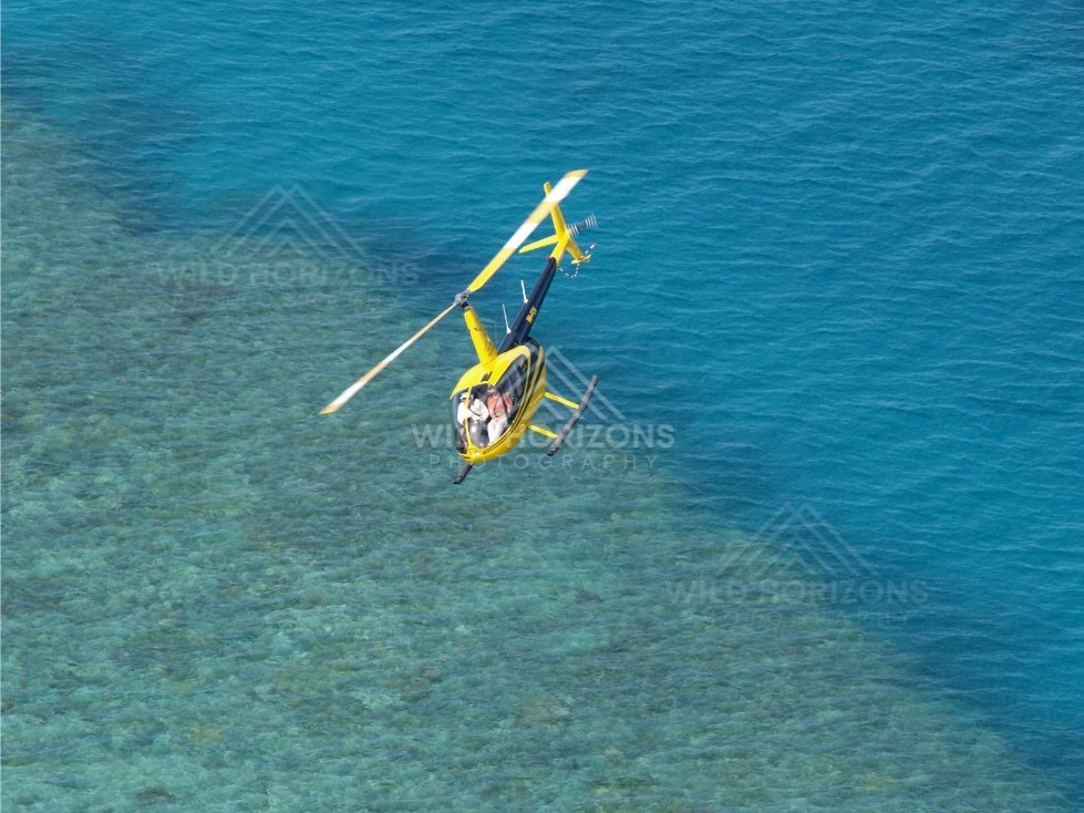 Single helicopter in flight over shallow sea. Thursday Island, Queensland, Australia.