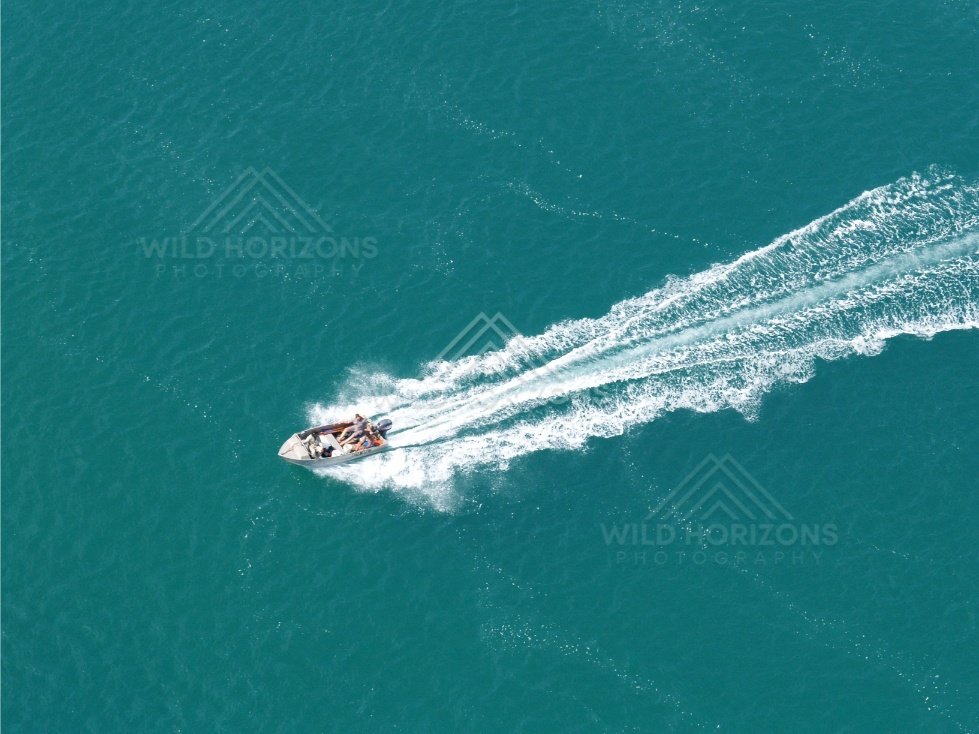 Small boat leaving wake across blue water. Thursday Island, Queensland, Australia.